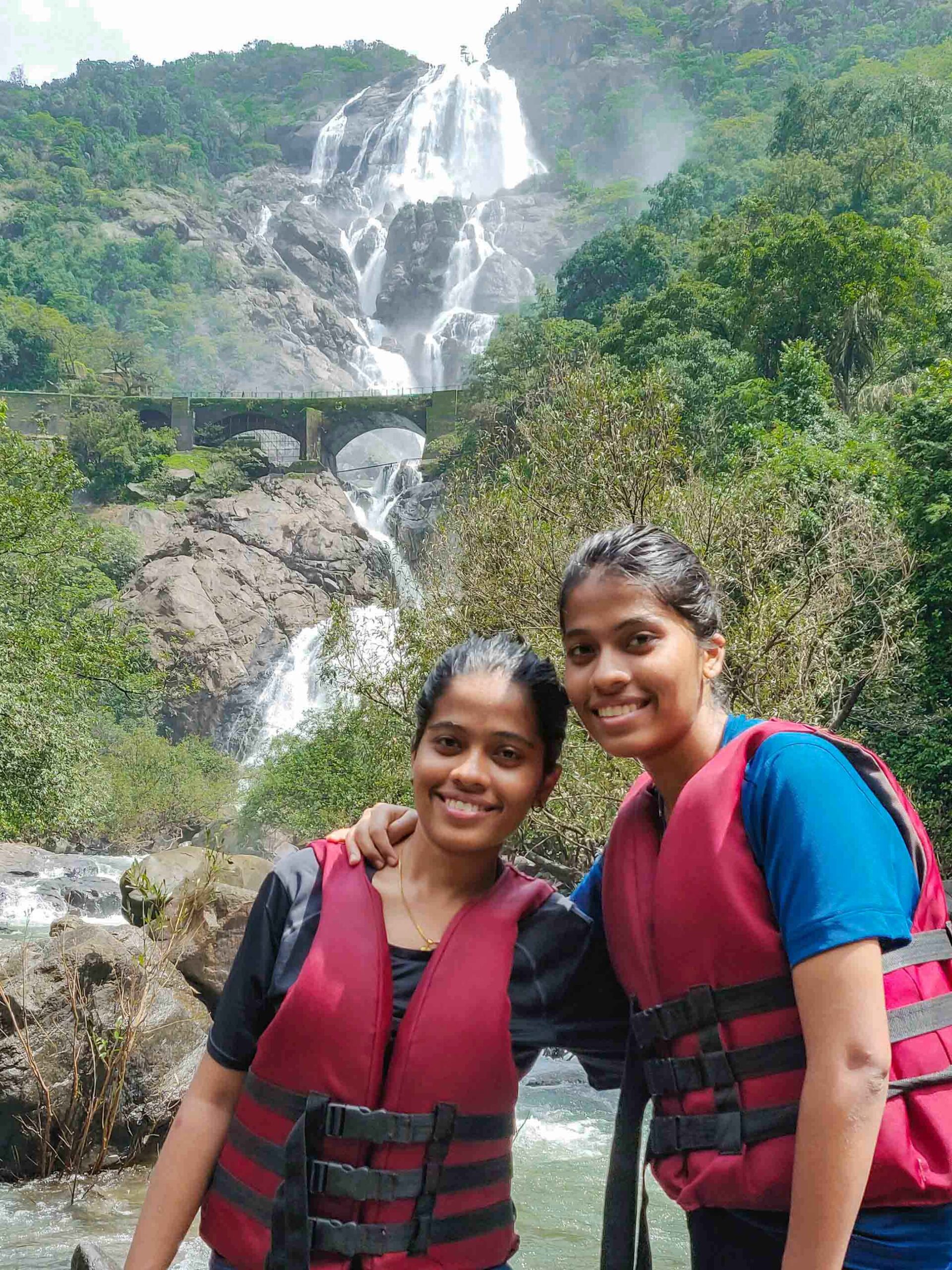 Twin standing in front of the Dudhsagar waterfall during monsoon